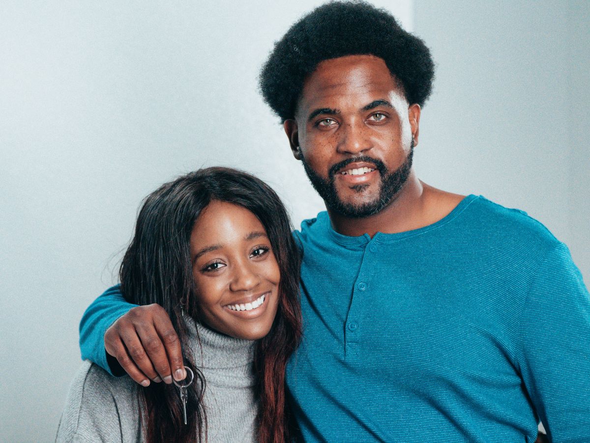 Couple souriant tenant des clés de leur nouveau logement après leur emménagement