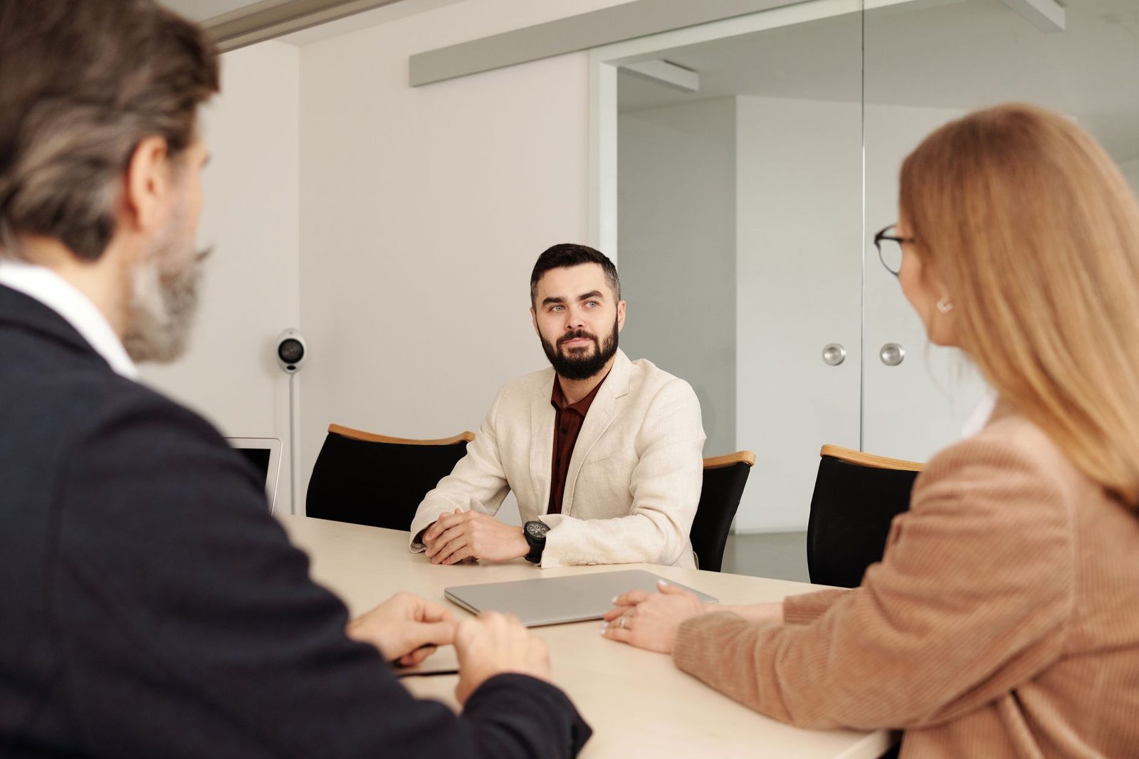 Jeune homme en entretien d'embauche face à deux recruteurs autour d'une table de réunion