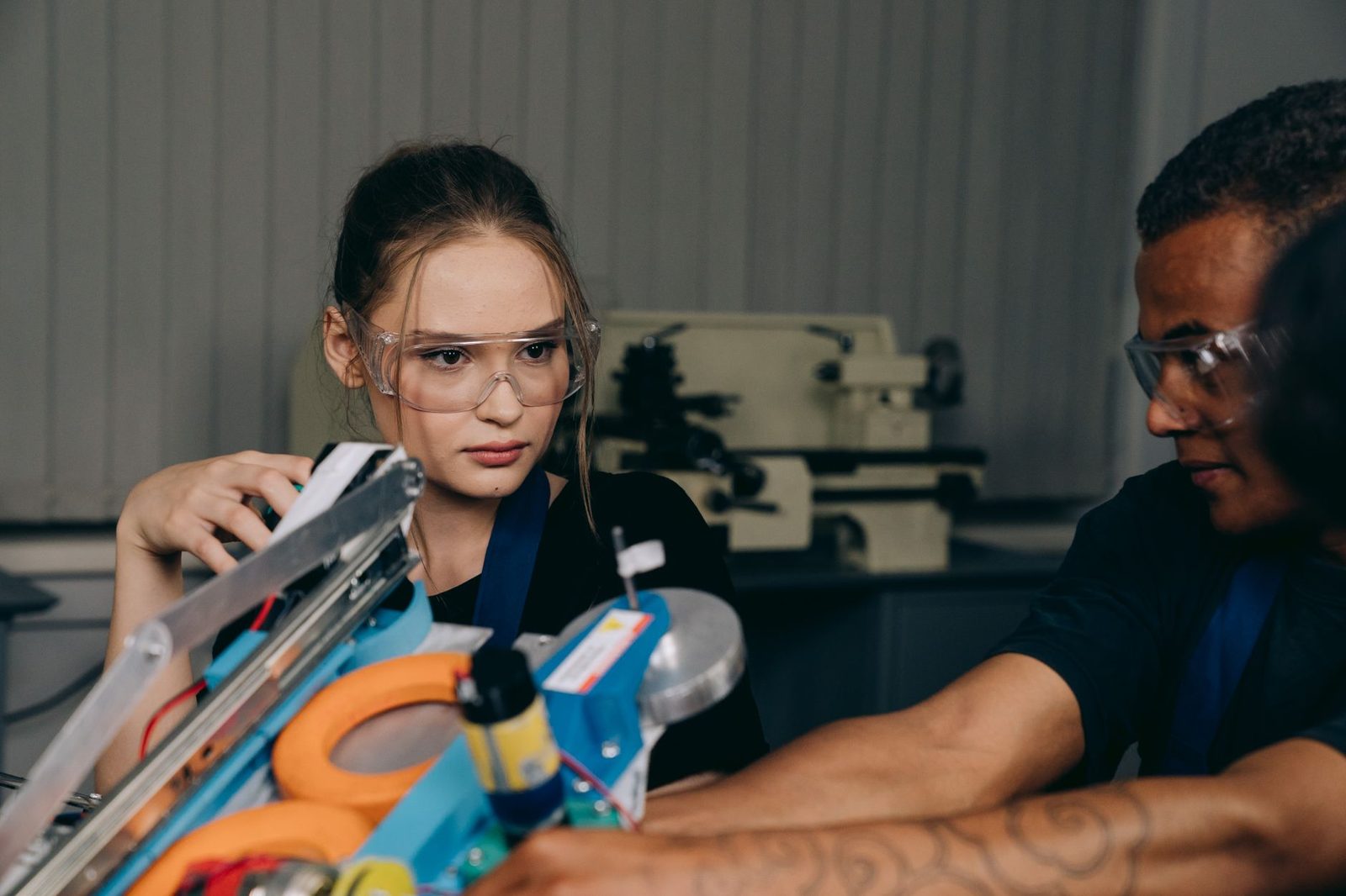 Deux jeunes en lunettes de protection manipulent un équipement technique dans un atelier