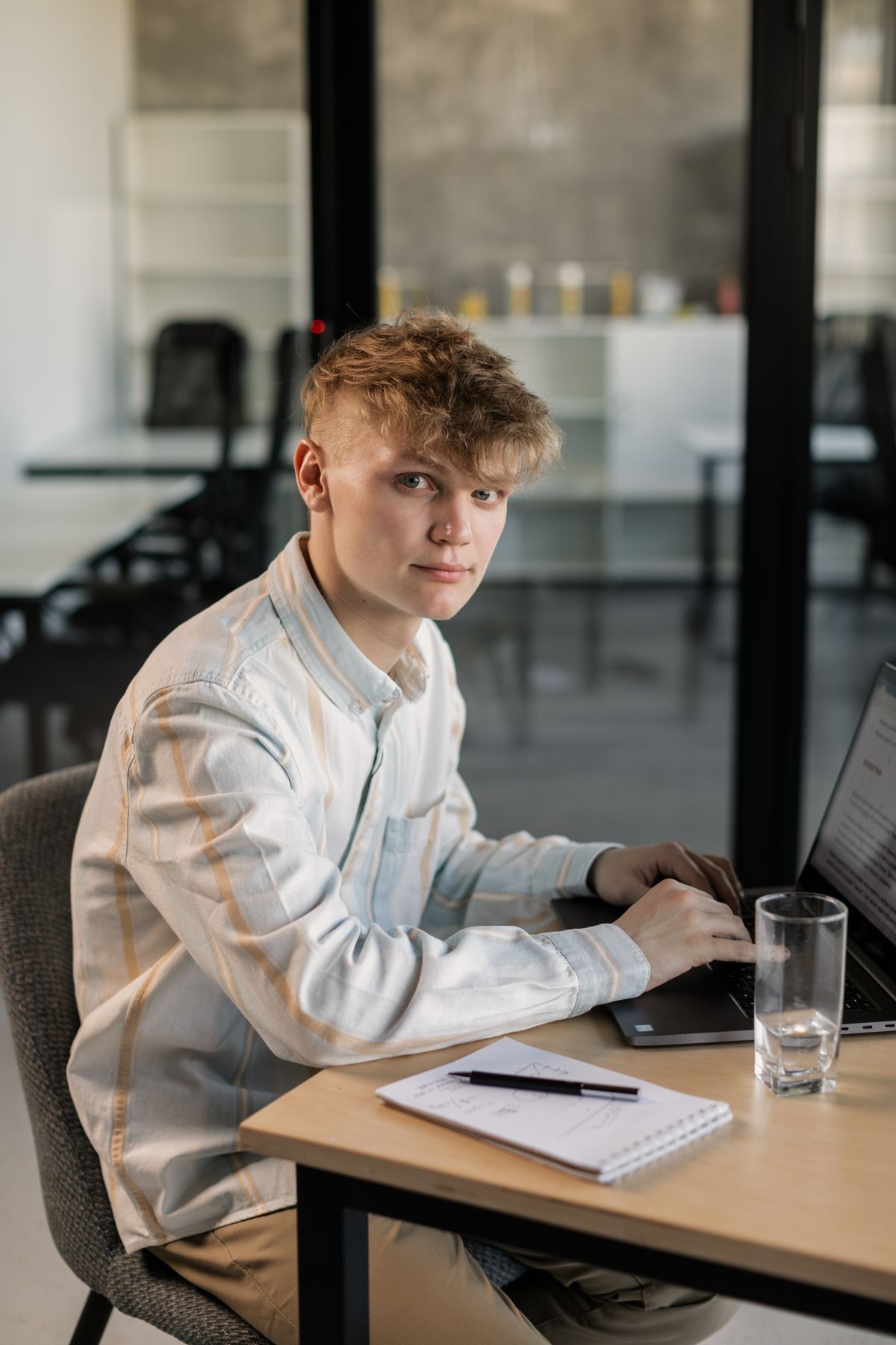 Młody praktykant pracujący na laptopie przy biurku, ilustrujący stanowisko w trybie przemiennym w służbie publicznej