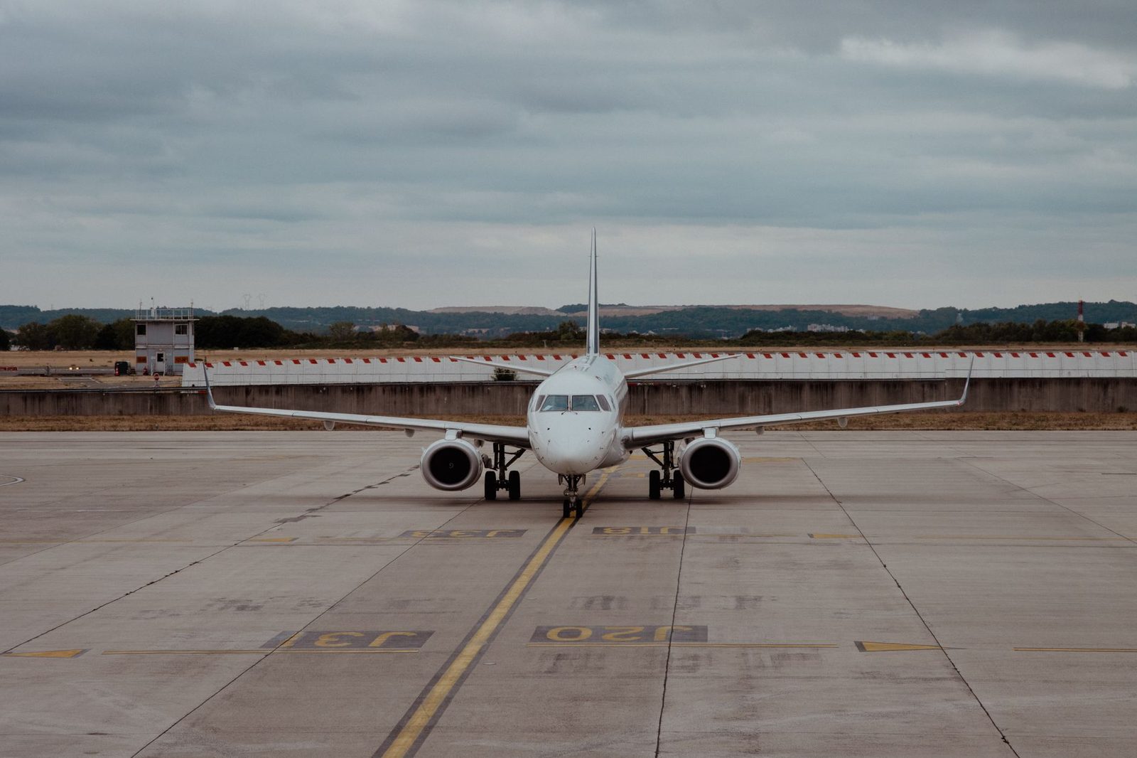 Witte passagiersvliegtuig dat over het platform van een luchthaven taxiet onder een bewolkte hemel