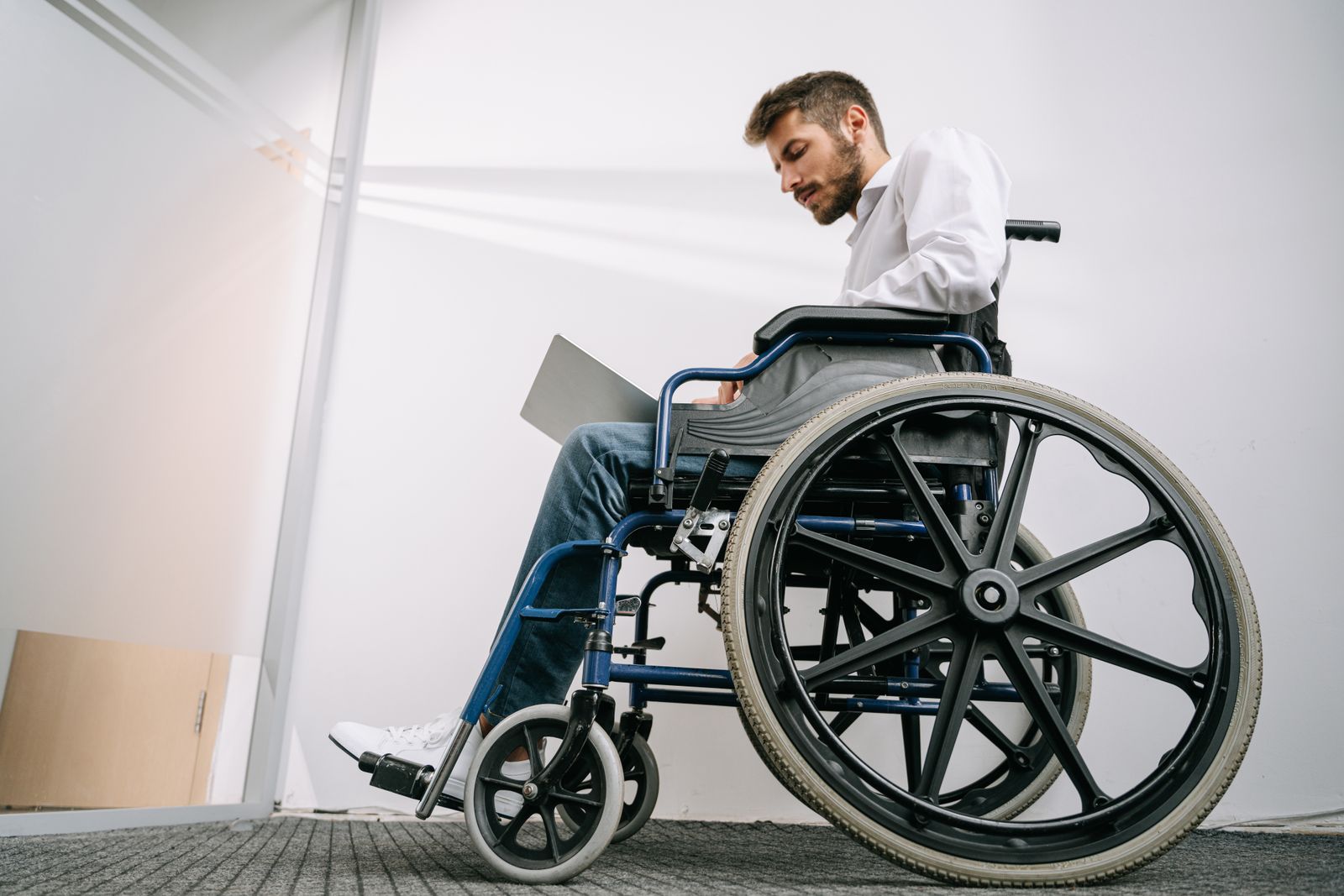 Giovane professionista in sedia a rotelle che lavora al computer portatile, a illustrare l'alternanza accessibile alle persone con disabilità