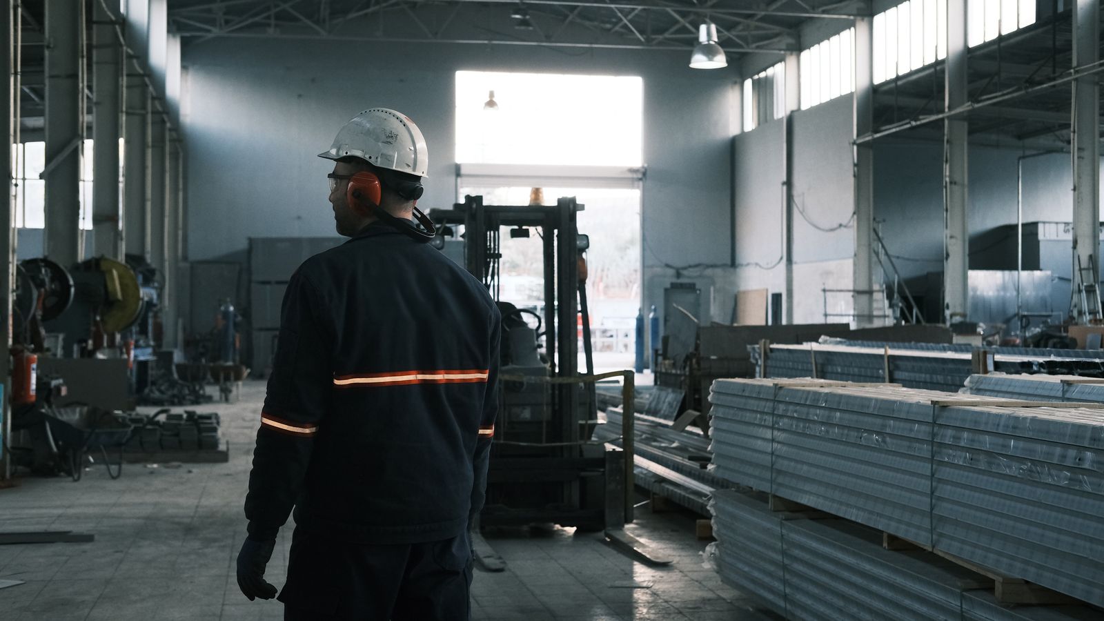 Tecnico industriale con dispositivi di protezione davanti a una macchina in una fabbrica moderna, a illustrare l'alternanza nell'industria