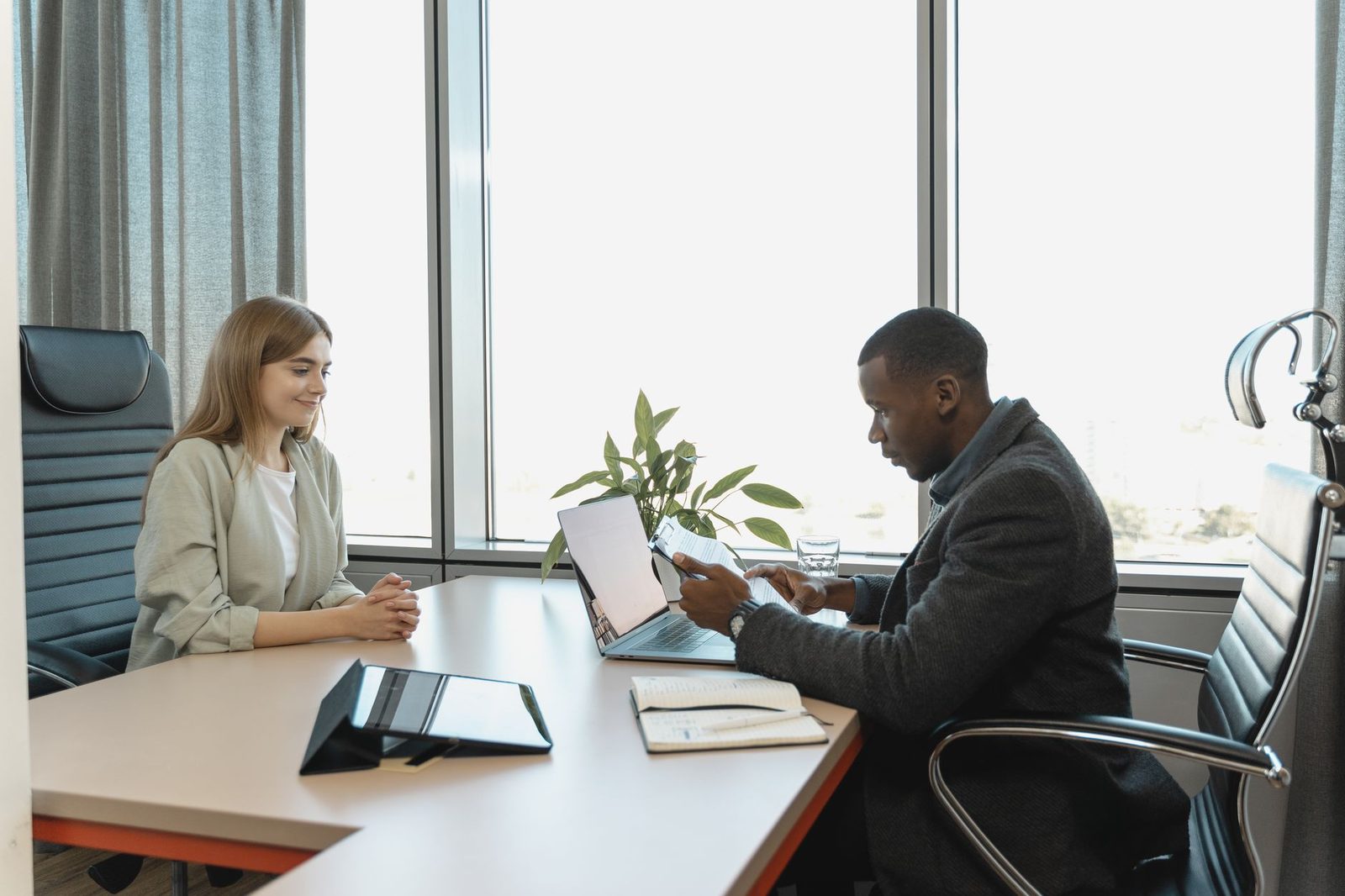 Entretien de recrutement entre une jeune candidate et un recruteur consultant un CV dans un bureau