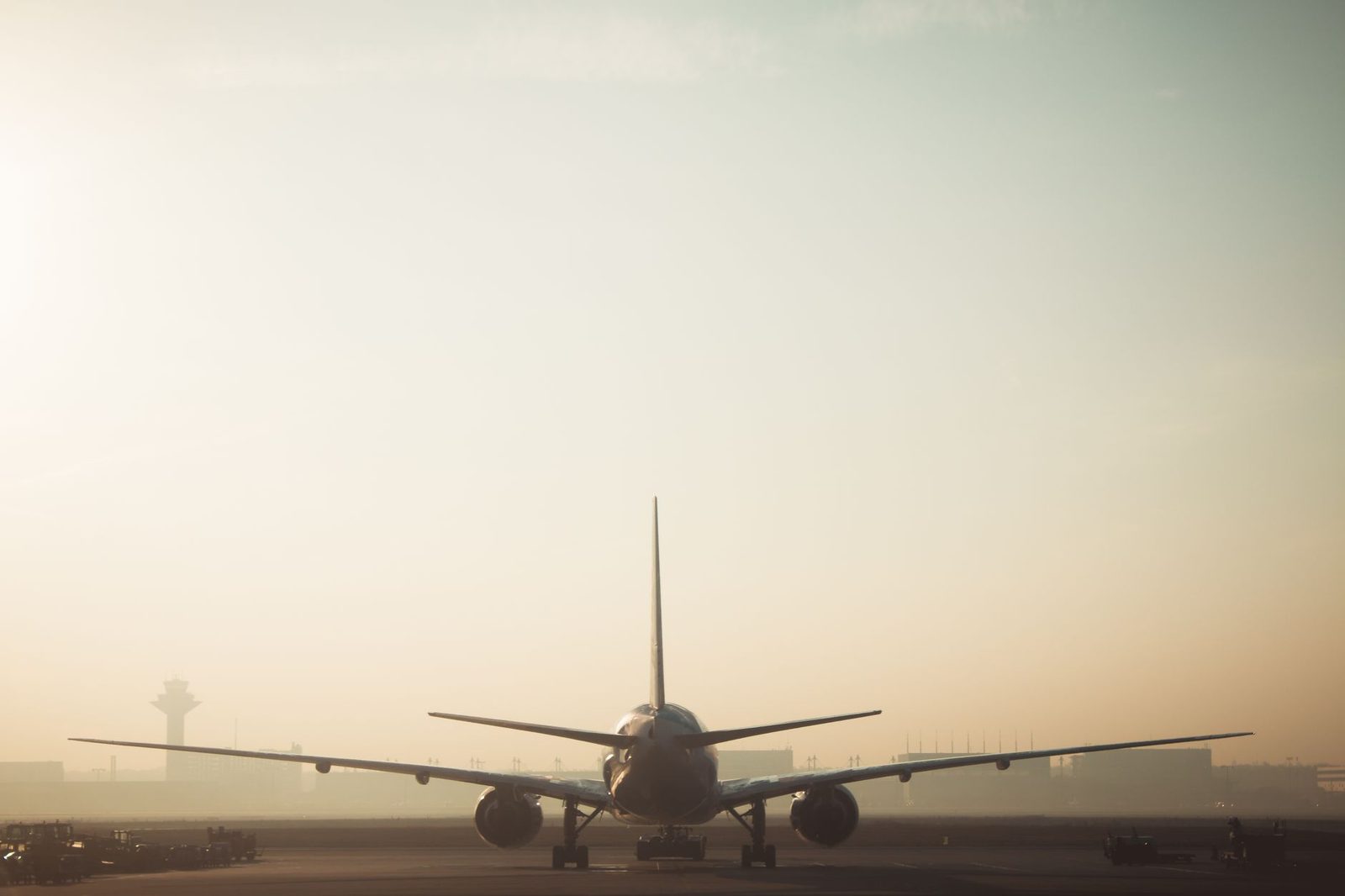 Avion de ligne vu de dos sur le tarmac d'un aéroport au lever du soleil, tour de contrôle en arrière-plan