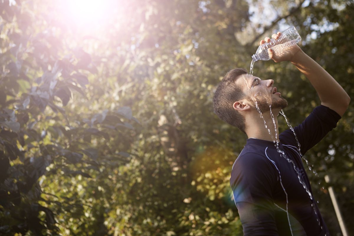 Worker pouring water on his head to cool off in the sun, a reminder of essential gestures during a heatwave at work