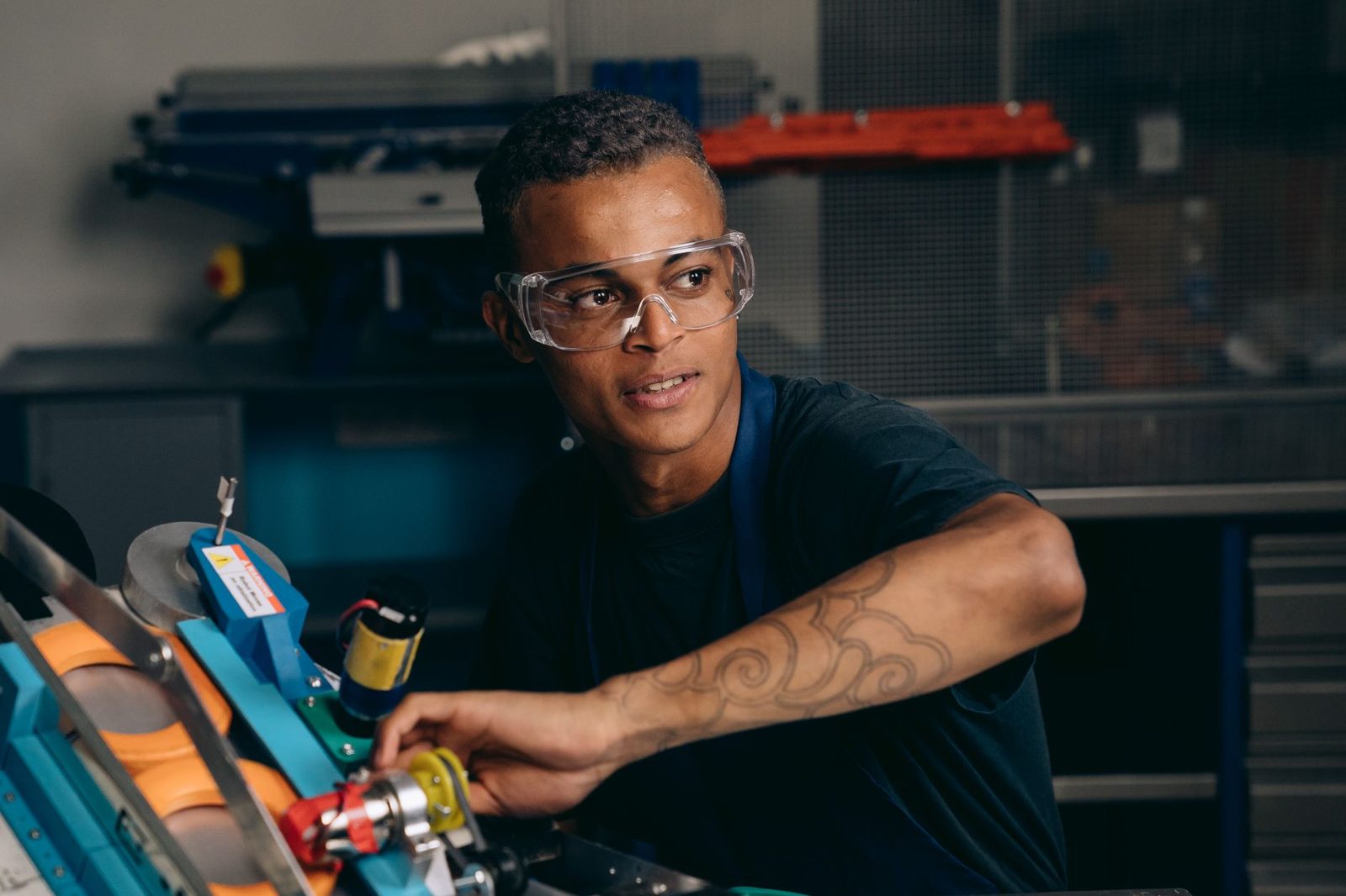 Jovem com óculos de proteção a trabalhar numa máquina numa oficina