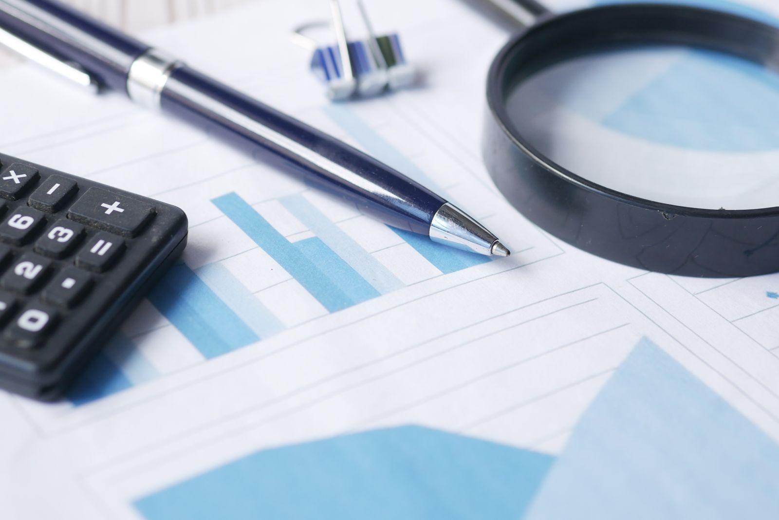 Calcolatrice, penna e lente d'ingrandimento posate su documenti amministrativi finanziari