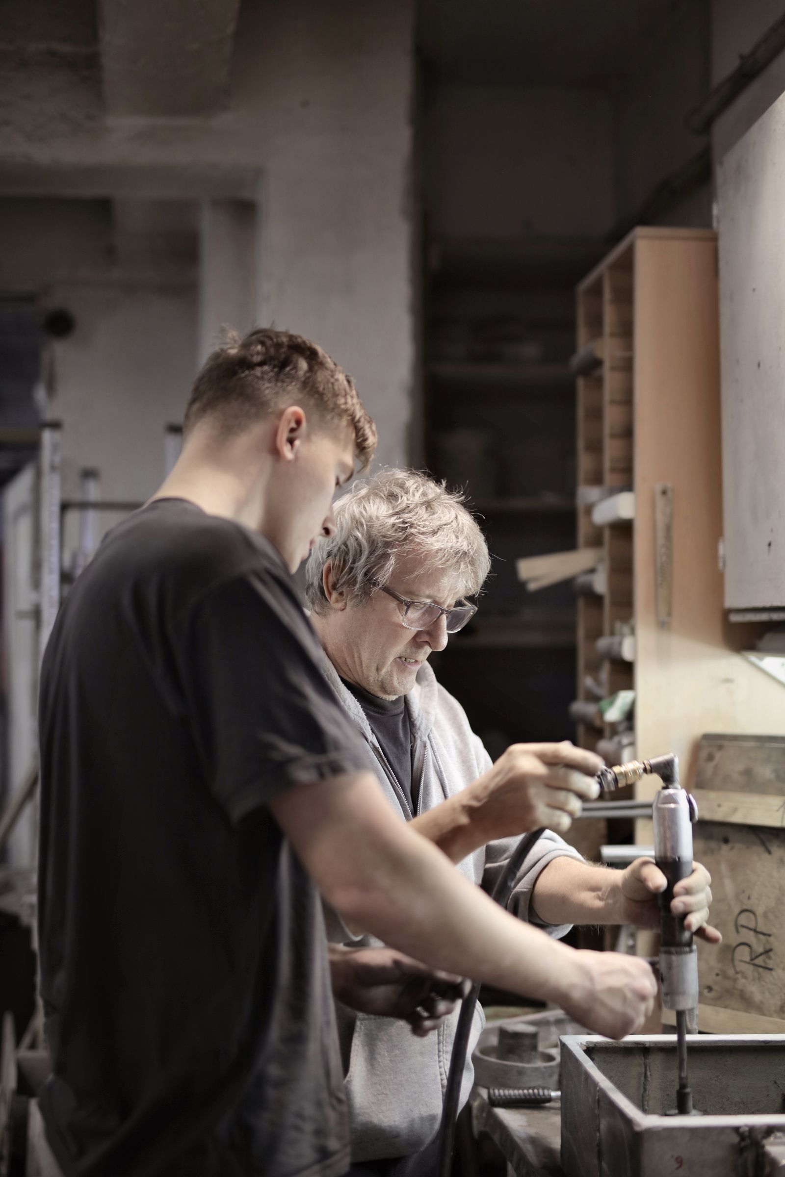 Un maestro di apprendistato esperto forma un giovane apprendista su una macchina in un'officina
