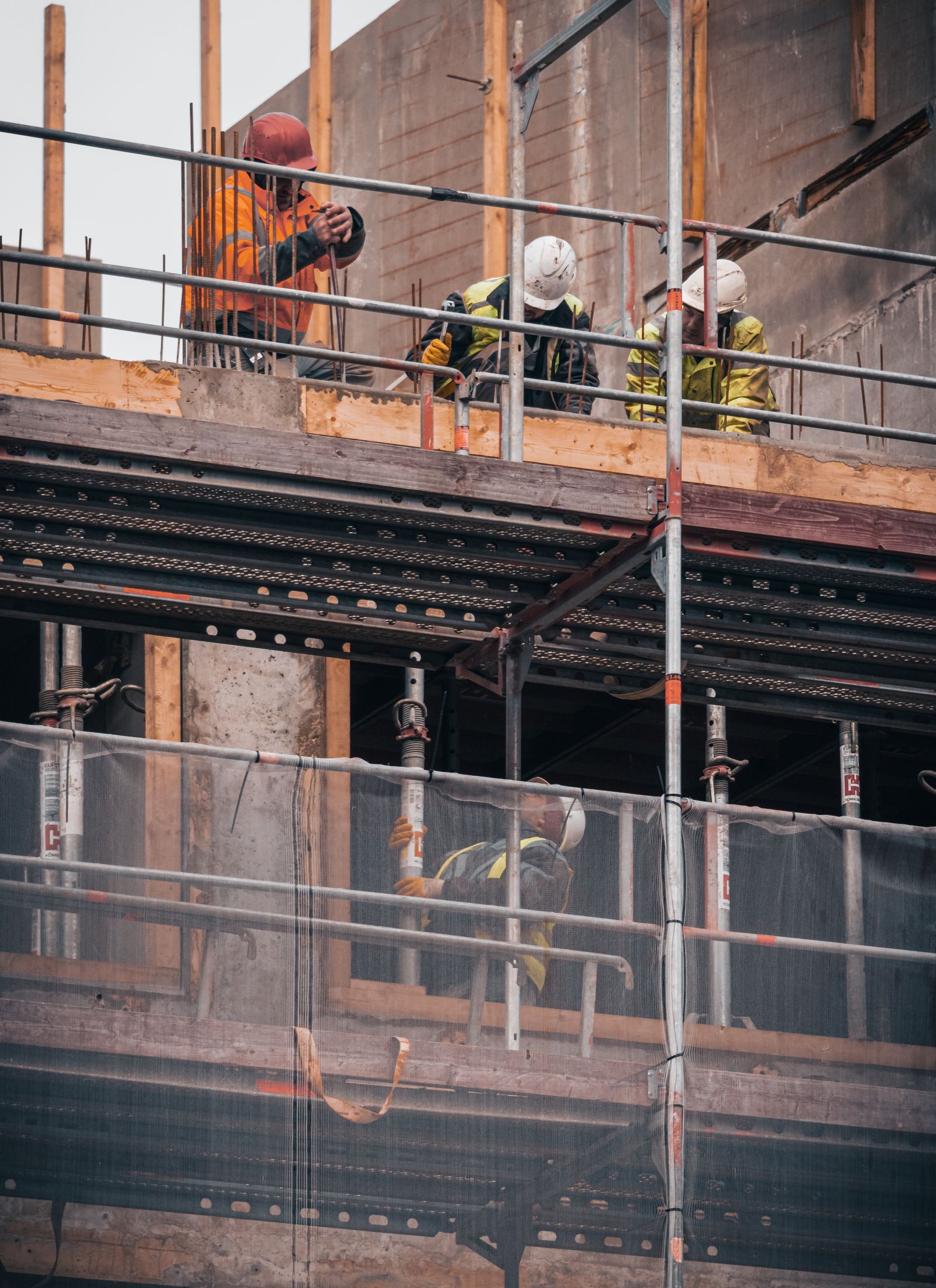 Construction worker in a high-visibility vest checking formwork plans on a building site under construction