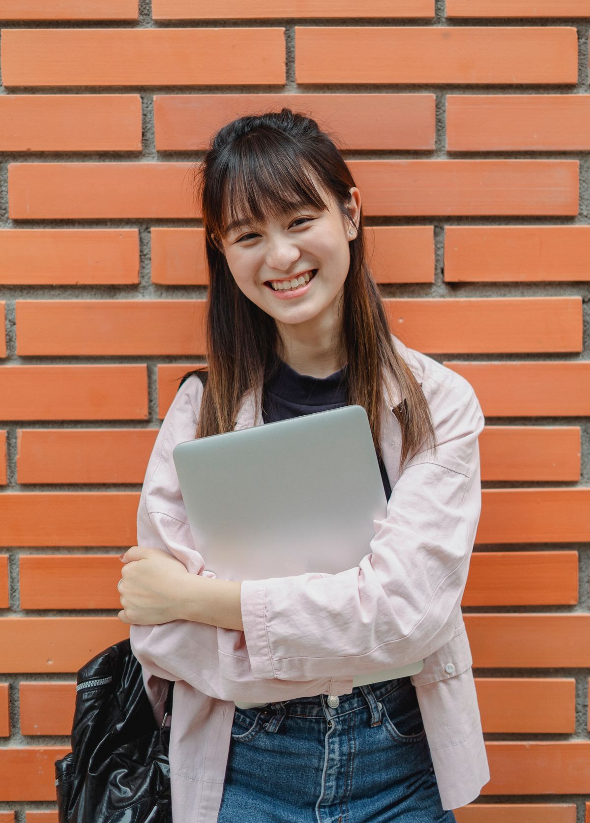 Estudante sorridente a consultar o seu computador portátil depois de formular novas candidaturas na fase complementar