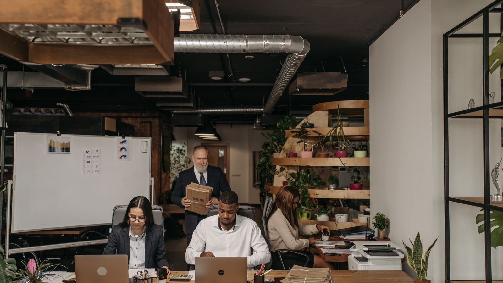 A team of four people working together in a large company's open space, symbolising new work-study hires