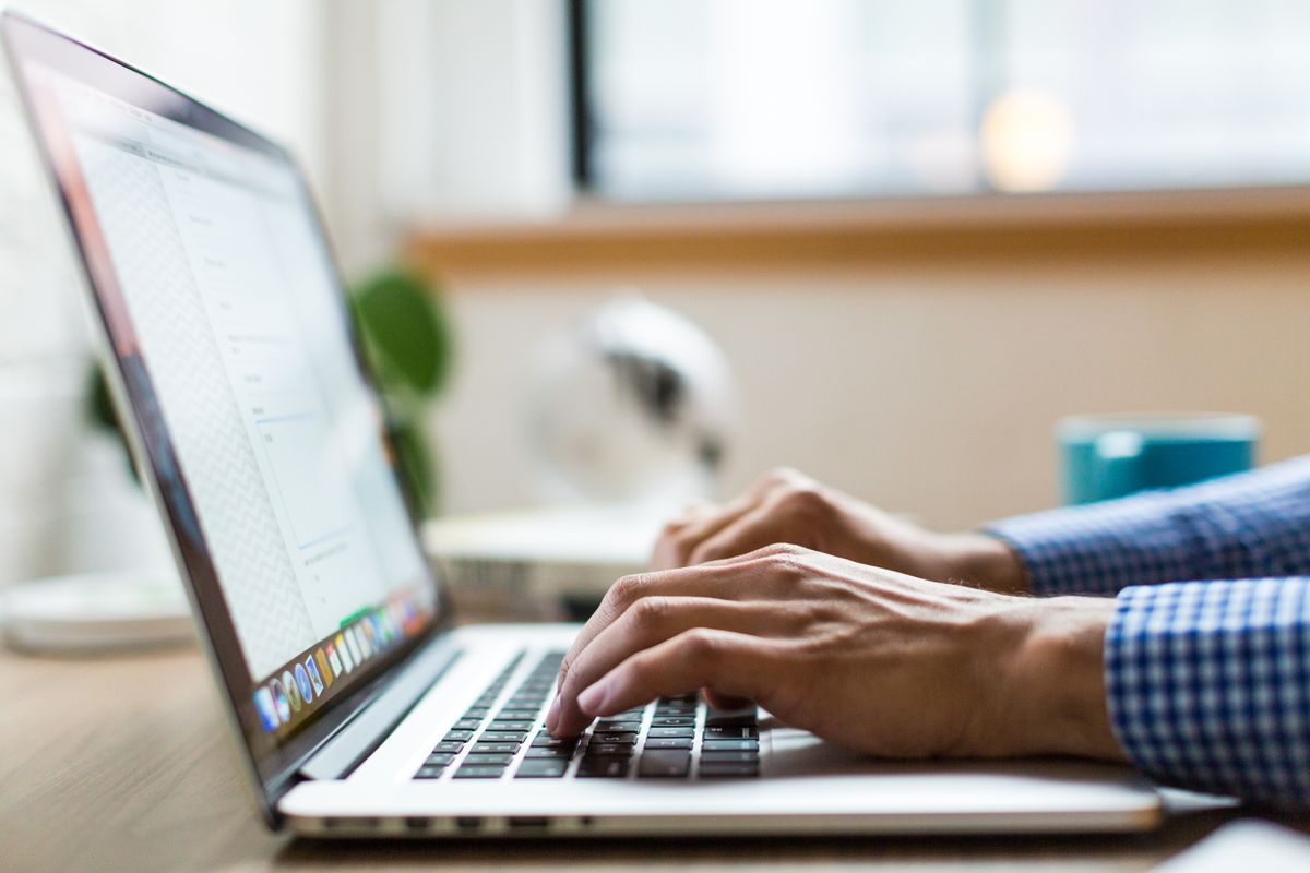 Giovane professionista che scrive un'email di follow-up sul portatile in uno spazio di lavoro moderno