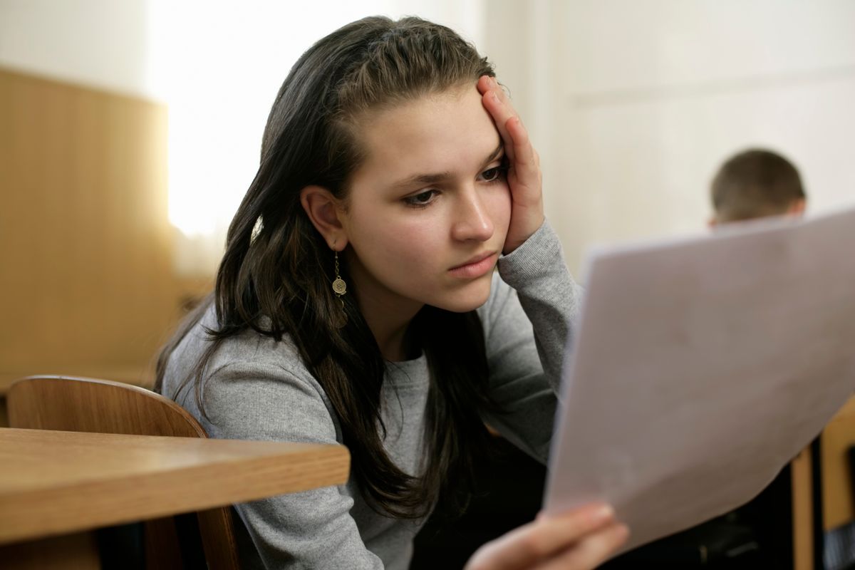 Giovane donna che legge con attenzione un documento, come una pagella d'esame