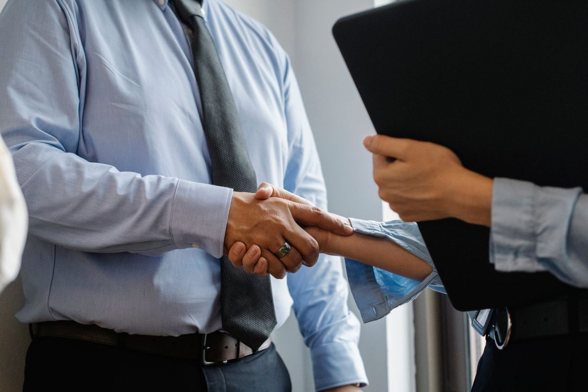 Recruiter e giovane apprendista che si stringono la mano in un ufficio dopo un'assunzione riuscita